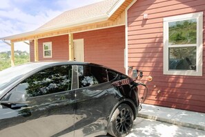Un coche negro estacionado frente a una casa roja con puerta de garaje y ventana.