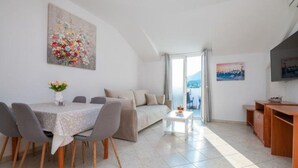 Ein modernes Wohnzimmer mit Essbereich, einer Couch, einem Couchtisch und einem Fernseher.
