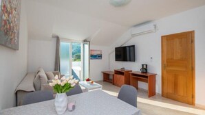 Ein modernes Wohnzimmer mit Esstisch, Sofa und Wandfernseher.