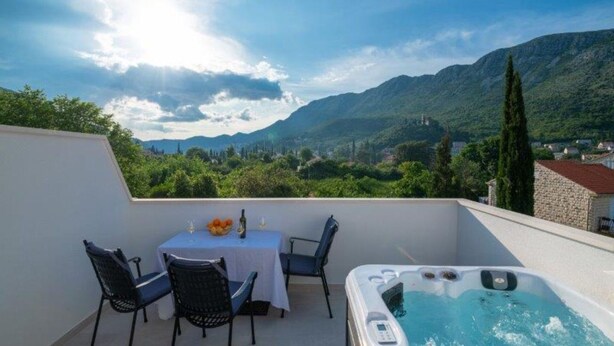 Ein Balkon mit Tisch und Stühlen, einem Whirlpool und Blick auf die Berge.