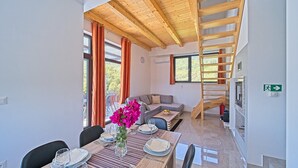 Un interior moderno con zona de comedor, sofá, escalera y vistas al exterior.