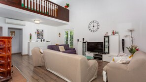 A living room with a sofa, TV, and a clock on the wall.