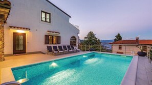 Area piscina con edificio bianco, piscina e vista sul mare.