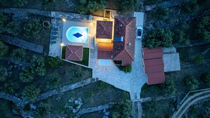 Une vue aérienne d’une propriété dotée d’une piscine, de plusieurs bâtiments aux toits rouges et d’une voiture garée à proximité.