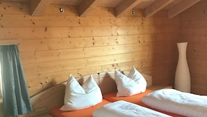 Ein Schlafzimmer einer Holzhütte mit einem Bett, Kissen, einem Nachttisch und einer Vase.