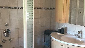 Ein Badezimmer mit Dusche, Toilette, Waschbecken und Waschtisch.