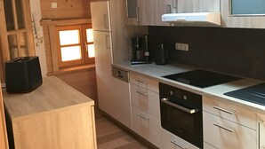Eine moderne Küche mit Holzausstattung, einem eingebauten Ofen und einer Kaffeemaschine.