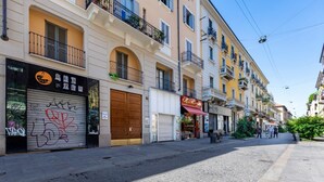A street with buildings, closed shop shutters, and a clear sky. - GuestHost - Simplon & Garibaldi Comfy Studio (Milano)