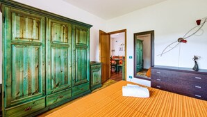 A bedroom with a large bed, a wardrobe, a mirror, and a door leading to a bathroom.