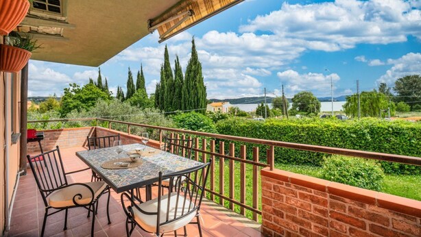 A balcony with a table and chairs, a view of the landscape, and a clear sky.