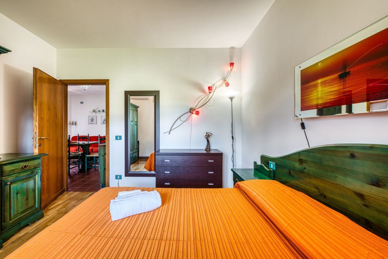 Ein Schlafzimmer mit Bett, Kommode, Spiegel und Bildern an der Wand.