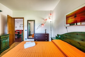 Una camera da letto con un letto, una cassettiera, uno specchio e opere d'arte alle pareti.