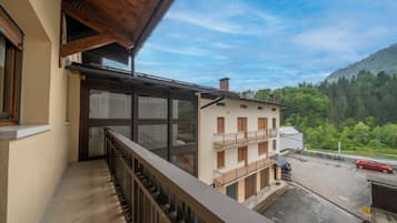 Un balcone con vista su un edificio e una montagna ricoperta di alberi.