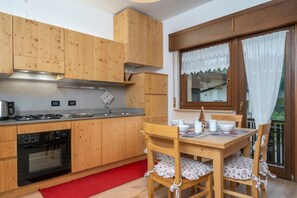 A kitchen with wooden cabinets, a stove, oven, and a dining table with chairs.