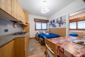 Une pièce compacte comprenant un coin cuisine, un lit, une table à manger et un canapé.