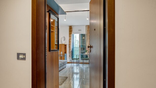 A hallway leading to a living area with a sofa, chairs, and a glass door. - GuestHost - Comfortable apartment equipped with all comforts to accommodate up to 3 people, located a stone's throw from Fontivegge Station (80 meters) and a 5-minute walk from Pescaia Park. It is located in a quiet residential area well equipped with al (Perugia)