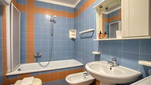 A bathroom with a bathtub, two sinks, a toilet, and a mirror. - GuestHost - Comfortable apartment equipped with all comforts to accommodate up to 3 people, located a stone's throw from Fontivegge Station (80 meters) and a 5-minute walk from Pescaia Park. It is located in a quiet residential area well equipped with al (Perugia)