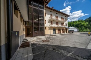 A building with large windows, a balcony, and a parking area.