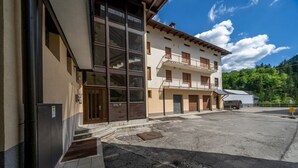 A building with large windows, a balcony, and a parking area. - GuestHost - Cozy Apartment X3 in Tarvisio Center (Tarvisio)