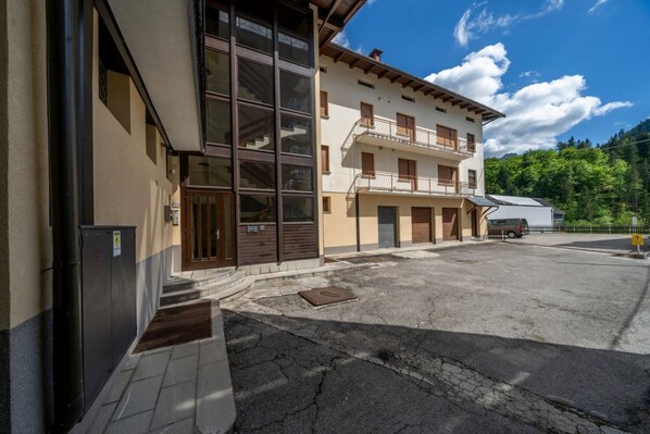 A building with large windows, a balcony, and a parking area.