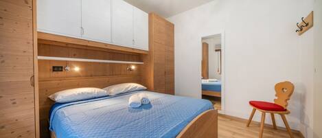 A bedroom with a bed, wooden wardrobe, and a chair.