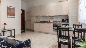 Une cuisine moderne avec des meubles en bois clair, un îlot central et un coin repas comprenant une table et des chaises.