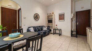 Un salon moderne comprenant une table à manger, un canapé, un meuble pour la télévision et un coin cuisine.