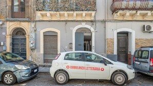Valkoinen auto, jonka kylkeen on maalattu teksti ”AMBULANZA LETTERARIA”, oli pysäköitynä mukulakivikadulle.