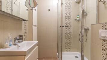 Ein Badezimmer mit Waschbecken, Spiegel, Dusche und Toilette.