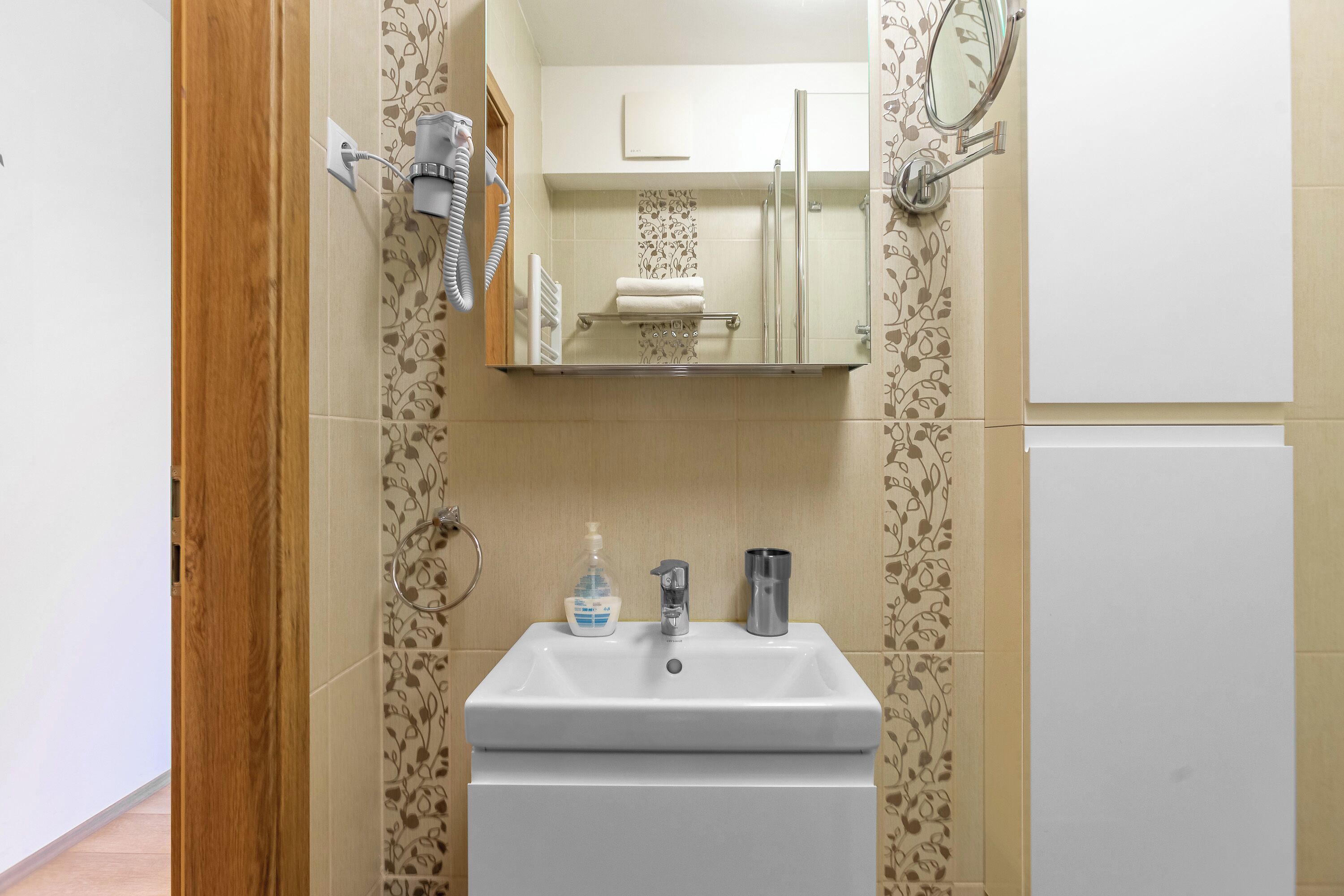 Un baño con un lavabo blanco, un espejo, toallero y ducha.