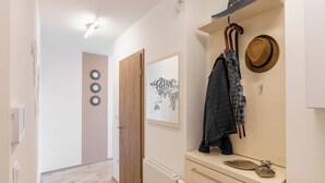 A hallway with a wooden door, a radiator, and a coat rack with hats and a jacket. - Sunset Resort 409 With Pool (Fonyod)