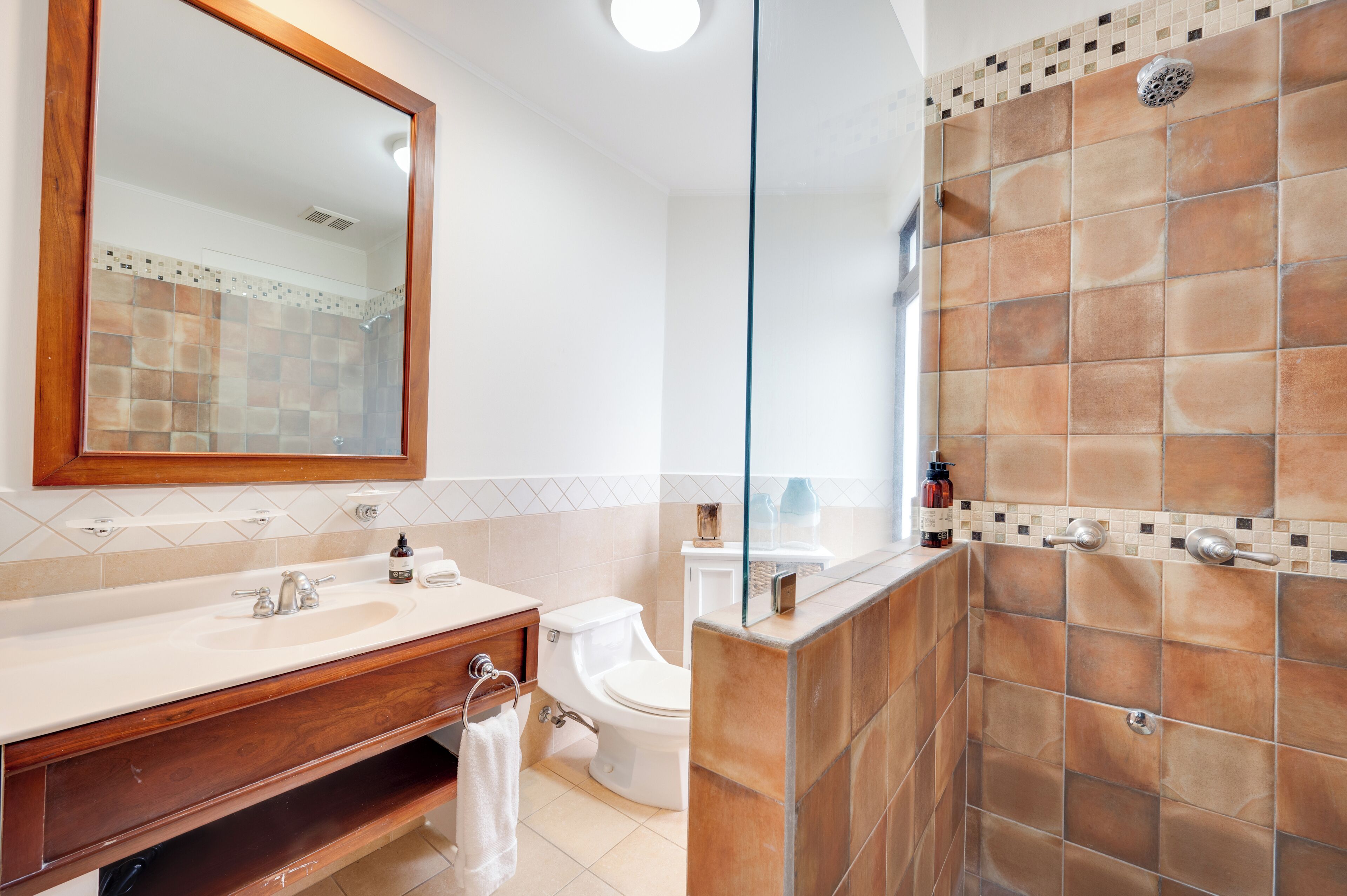 Ein Badezimmer mit großem Spiegel, Waschbecken, Toilette und Duschbereich.