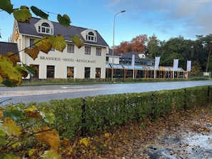 Classic hotel building with a pitched roof and symmetrical facade, adjacent to a road.