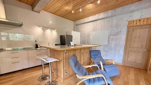 A modern kitchen with a wooden ceiling, a bar area with stools, and a large whiteboard on the wall.