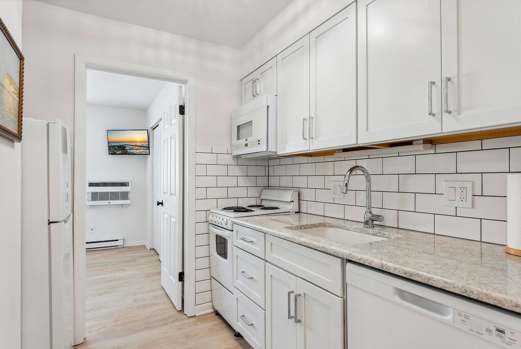 A modern kitchen with white cabinets, a granite countertop, and a built-in oven.