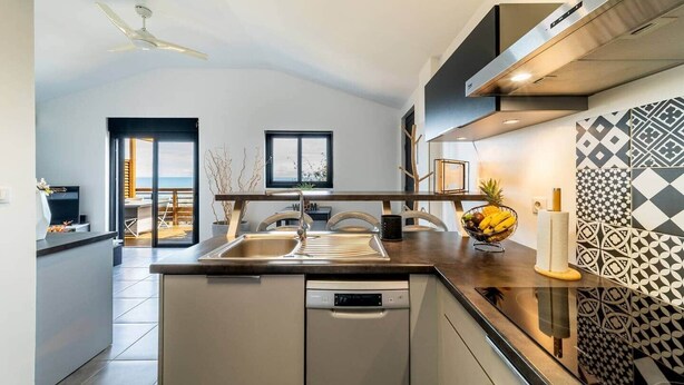 A modern kitchen with a central island, a dishwasher, and a view to the outside.