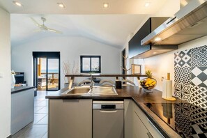 Cozinha moderna com ilha central, máquina de lavar louça e vista para o exterior.