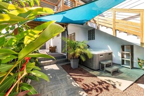 Um pátio com hidromassagem, plantas em vasos e um deck de madeira.