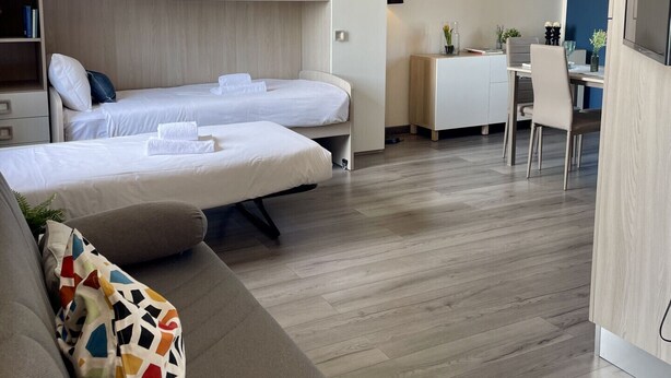 Une chambre d’hôtel moderne équipée d’un lit, d’un canapé, d’un bureau et d’un coin repas.