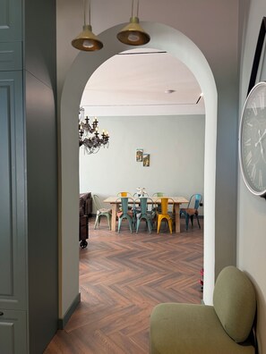 Un coin repas avec une table en bois, des chaises colorées et un lustre.
