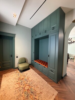 Une pièce dotée d’une banquette intégrée, d’un fauteuil vert, d’un tapis à motifs et d’un luminaire au plafond.