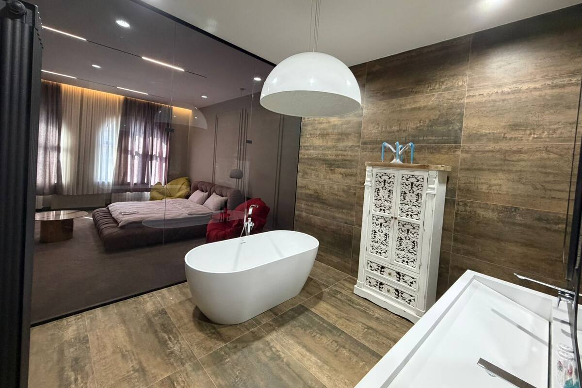 A modern bathroom with a freestanding bathtub, a white vanity, and a large mirror.