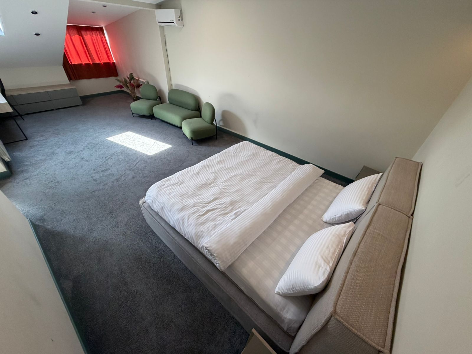 A hotel room with a bed, a sofa, a chair, and a small table.