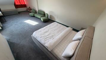 A hotel room with a bed, a sofa, a chair, and a small table.