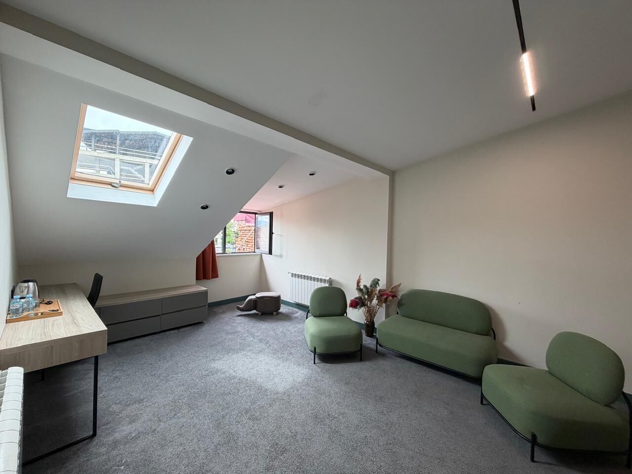 Une pièce moderne avec une lucarne, un canapé, une petite table et un radiateur.