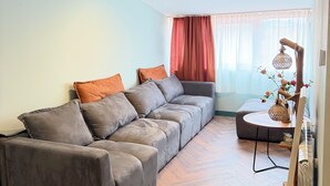 Un salon avec un canapé d’angle, une petite table ronde et un radiateur.
