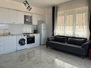 Departamento básico, balcón, vista parcial al mar | Área de sala de estar | Televisión LED de 32 pulgadas con canales por cable