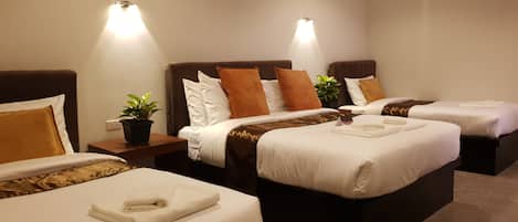 A hotel room with two beds, each with a brown headboard, white bedding, and a small potted plant on the nightstand.