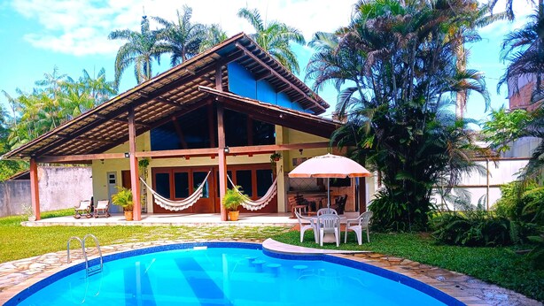 A house with a swimming pool, a covered patio, and a garden with palm trees. - AMAZON HOME AND JUNGLE TRIPS (Manaus)