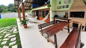 A patio area with a wooden bench, a hammock, and a brick fireplace. - AMAZON HOME AND JUNGLE TRIPS (Manaus)